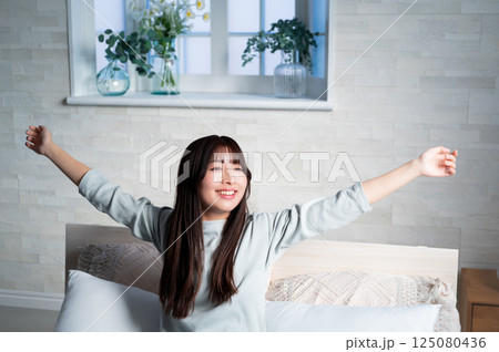 ベッドで伸びをする女性 125080436