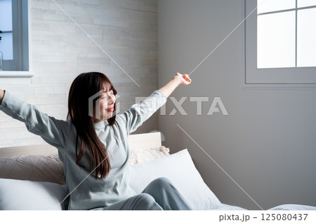ベッドで伸びをする女性 125080437