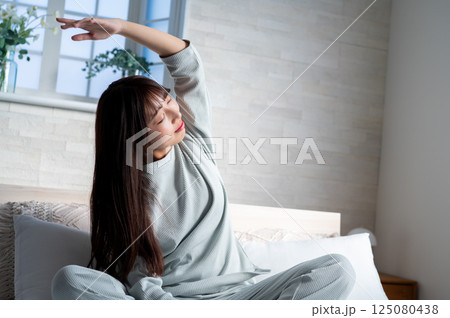 ベッドで伸びをする女性 125080438