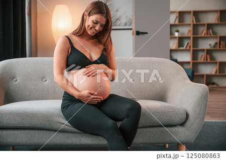 On the sofa. Beautiful pregnant woman is indoors at home On the sofa. Beautiful pregnant woman is indoors at home 125080863