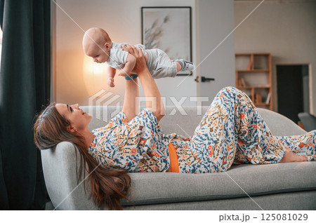 Holding child in the hands. Beautiful happy mother with her newborn son is at home Holding child in the hands. Beautiful happy mother with her newborn son is at home 125081029