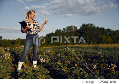 Quality control. WIth notepad and cabbage. Woman is on the agricultural field at daytime 125081046
