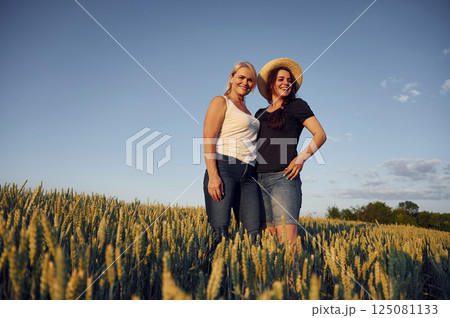 Two women standing on the agriculture field with growing wheat 125081133
