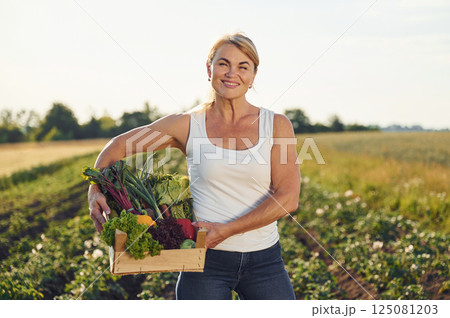 Cabbage, pepper, potato and onion in a basket. Woman is on the agricultural field at daytime Cabbage, pepper, potato and onion in a basket. Woman is on the agricultural field at daytime 125081203