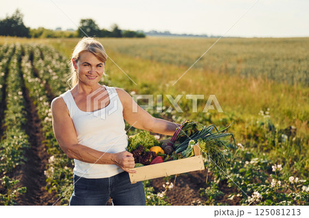 Harvest in hands. Pepper, onion, potato and cabbage. Woman is on the agricultural field at daytime 125081213
