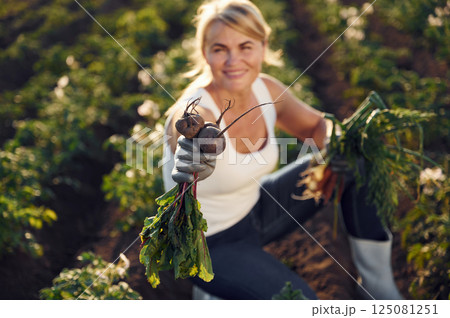 Onions, beetroots and carrots is in the hands. Woman is on the agricultural field at daytime Onions, beetroots and carrots is in the hands. Woman is on the agricultural field at daytime 125081251