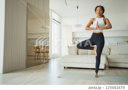 Yoga fitness workout training. Healthy African girl practicing yoga at home. Woman training Pilates doing sports exercise on yoga mat indoor. Girl have training workout for weight loss. Sport fitness 125081670