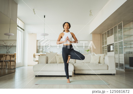 Yoga fitness workout training. Healthy African girl practicing yoga at home. Woman training Pilates doing sports exercise on yoga mat indoor. Girl have training workout for weight loss. Sport fitness 125081672