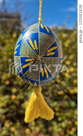Colorful Ukrainian pysanka featuring traditional patterns in national colors yellow blue, showcasing intricate design and vibrant Easter eggs hung against a beautiful natural background 125081838