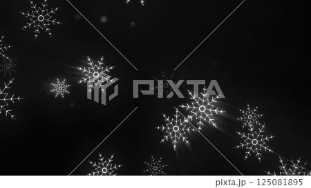 Bright white snowflakes illuminated against a dark black background, capturing a serene and frosty winter atmosphere 125081895