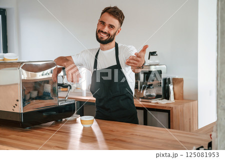 Beautiful portrait. Cafe worker in white shirt and black apron is indoors 125081953