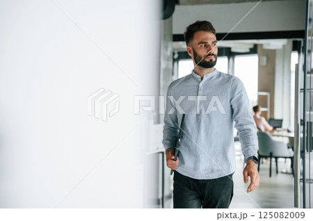With laptop in hand. Young office worker in formal clothes is indoors 125082009