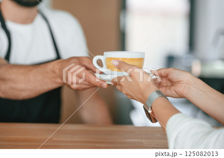 Close up view. Customer takes her order from barista in the cafe 125082013