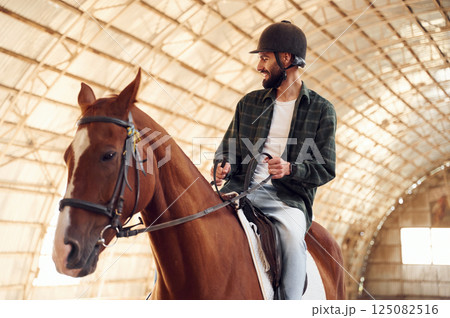Riding the horse. Young man is in the hangar Riding the horse. Young man is in the hangar 125082516