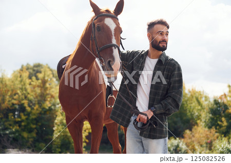 In casual clothes. Young man with a horse is outdoors 125082526