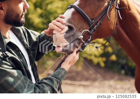 Young man with a horse is outdoors 125082535