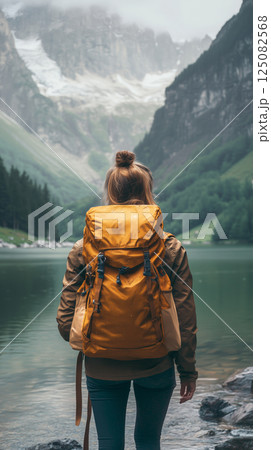 Girl traveler explores a serene hiking trail by a crystal-clear lake 125082568
