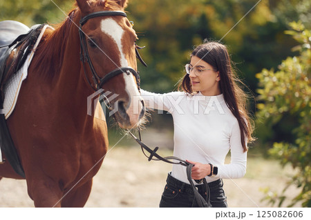 Touching the animal. Young beautiful woman with a horse is outdoors Touching the animal. Young beautiful woman with a horse is outdoors 125082606