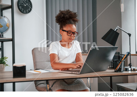 Using laptop. Cute female african american student child is sitting by the table 125082636