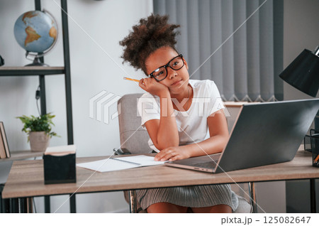Feeling bored. Cute female african american student child is sitting by the laptop Feeling bored. Cute female african american student child is sitting by the laptop 125082647