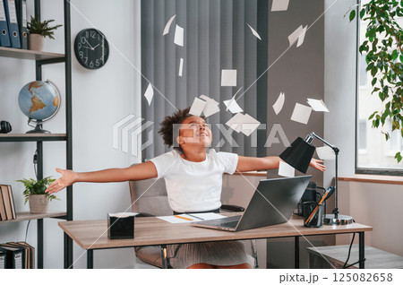 Throwing stickers up in the air. Celebrating success. Cute female african american student child is sitting by the laptop Throwing stickers up in the air. Celebrating success. Cute female african american student child is sitting by the laptop 125082658