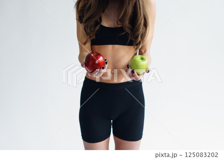 Sporty woman with perfect body holding green and red apples. Healthy low calorie meals, fresh fruits 125083202