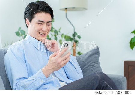 リビングでスマートフォンを使う男性 125083800