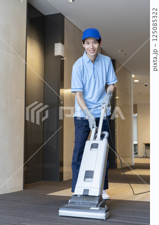 業務用カーペット用掃除機で作業をする若い男性クリーニングスタッフ　カメラ目線 125085322