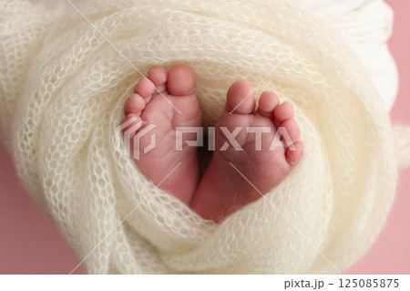 Close up of toes, heels and feet of a newborn baby.The tiny foot of a newborn. Soft feet of a newborn in a white blanket, pink background. Close up of toes, heels and feet of a newborn baby.The tiny foot of a newborn. Soft feet of a newborn in a white blanket, pink background. 125085875