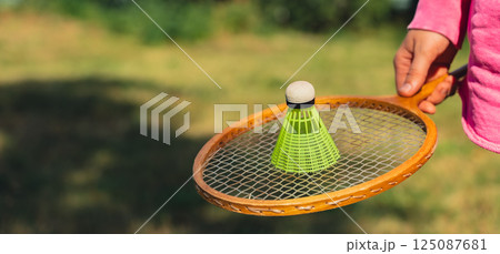 Woman hand holding wooden Badminton racket and shuttlecock. Outside recreation and fresh air. Healthy lifestyle nature connection sport summer activities. Stress relief hobby Woman hand holding wooden Badminton racket and shuttlecock. Outside recreation and fresh air. Healthy lifestyle nature connection sport summer activities. Stress relief hobby 125087681