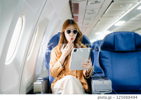 Smiling woman in first-class airplane seat, showcasing luxury, comfort, and elegance in travel. 125088494