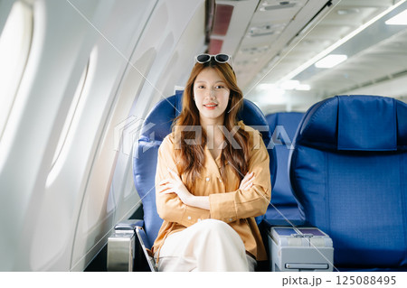 Smiling woman in first-class airplane seat, showcasing luxury, comfort, and elegance in travel. Smiling woman in first-class airplane seat, showcasing luxury, comfort, and elegance in travel. 125088495