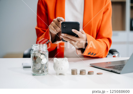 businesswoman holding coins putting in glass with using smartphone and calculator to calculate concept saving money businesswoman holding coins putting in glass with using smartphone and calculator to calculate concept saving money 125088600