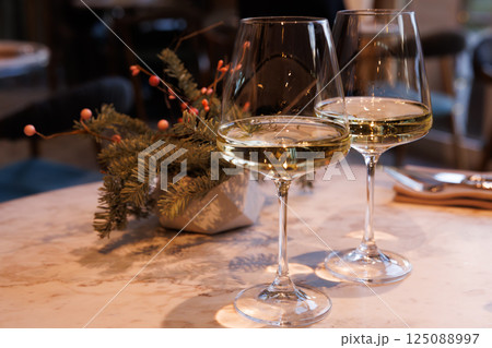Enjoying elegant white wine in a cozy restaurant setting with greenery and soft lighting Enjoying elegant white wine in a cozy restaurant setting with greenery and soft lighting 125088997