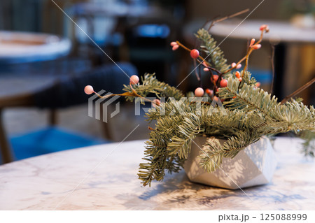 Charming tabletop decor with greenery and berries creating a cozy ambiance in a vibrant restaurant setting 125088999