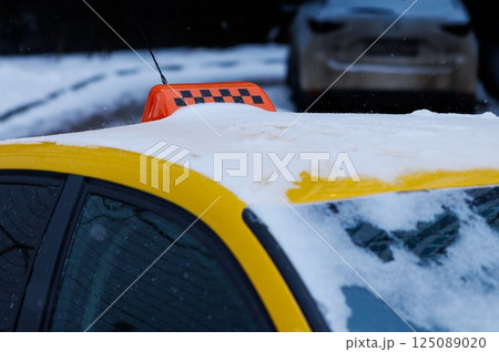 City taxi parked under a gentle snowfall highlighting a winter wonderland ambiance in a quiet urban street 125089020
