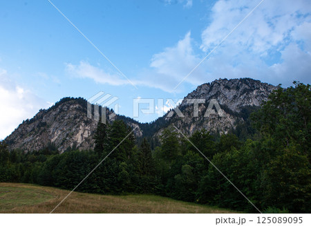 Majestic mountains rise against a vibrant sky near Neuschwanstein in Germany during golden hour 125089095