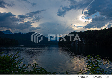 Majestic twilight over tranquil waters near Neuschwanstein Castle in Germany with dramatic cloud formations 125089096