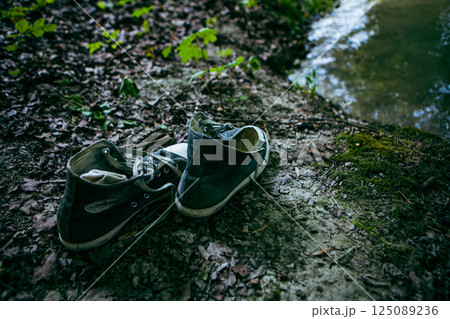 Forgotten footsteps by the serene riverbank surrounded by lush greenery in late afternoon light Forgotten footsteps by the serene riverbank surrounded by lush greenery in late afternoon light 125089236