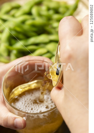 缶ビールを手酌でグラスに注ぐ 缶ビールを手酌でグラスに注ぐ 125089802