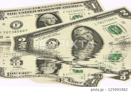Water Reflection US Dollar Bills. Conceptual Finance Background. Creative conceptual image of US dollar bills partially submerged in water with a water reflection effect.  125091982