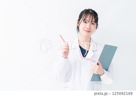 クリニックを紹介する指差しポーズの女性医師　白バック 125092189