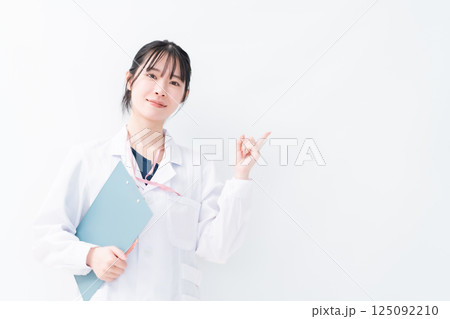 クリニックを紹介する指差しポーズの女性医師　白バック 125092210
