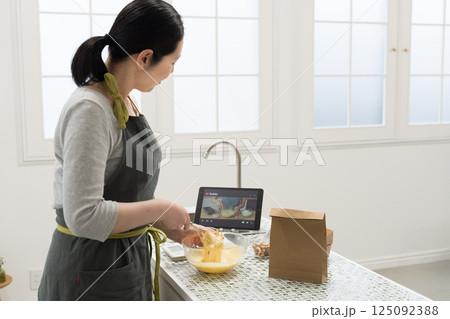 動画サイトを見ながらパウンドケーキを作る女性 125092388