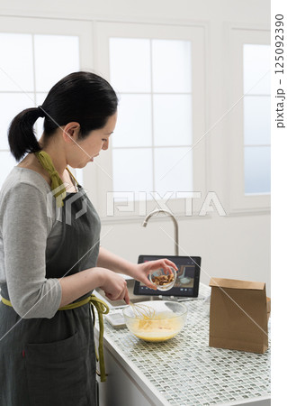 動画サイトを見ながらパウンドケーキを作る女性 125092390
