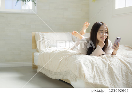 ベッドでスマホを見る女性 125092665