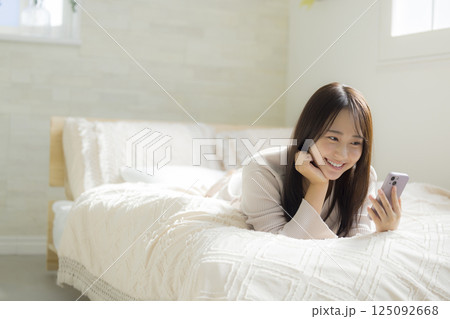 ベッドでスマホを見る女性 125092668
