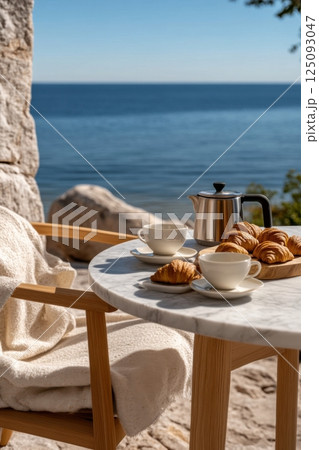 Serene seaside breakfast with croissants and coffee on a sunny morning 125093047