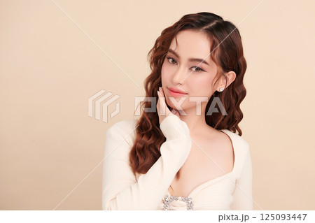 A beautiful young Asian woman with clean, fresh skin against a beige background. Skincare, facial treatment, cosmetology, beauty, and spa. An elegant portrait of an Asian woman. A beautiful young Asian woman with clean, fresh skin against a beige background. Skincare, facial treatment, cosmetology, beauty, and spa. An elegant portrait of an Asian woman. 125093447
