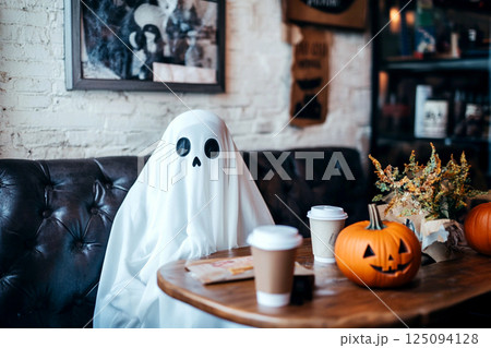 A spooky yet charming Halloween-themed coffee cup with ghost-shaped latte art, set against a warm, light background. Halloween parties, seasonal drinks, and creative cafe concepts 125094128